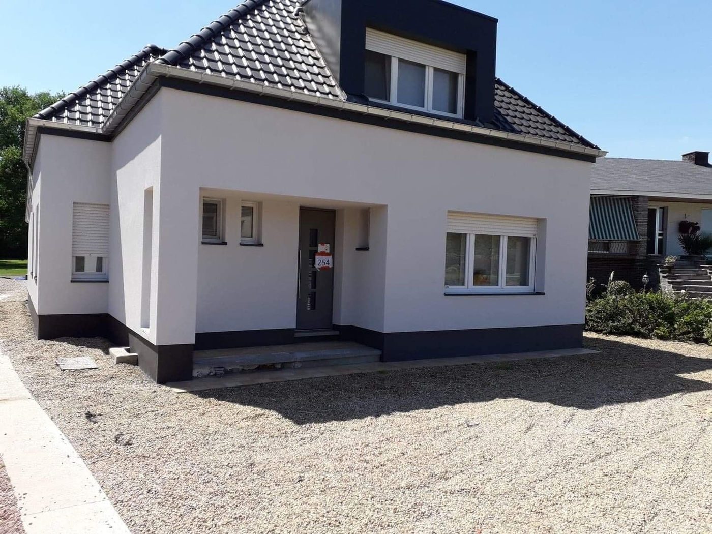 Woning met witte gevelbepleistering en donkere plint, uitgevoerd door Facade Concept