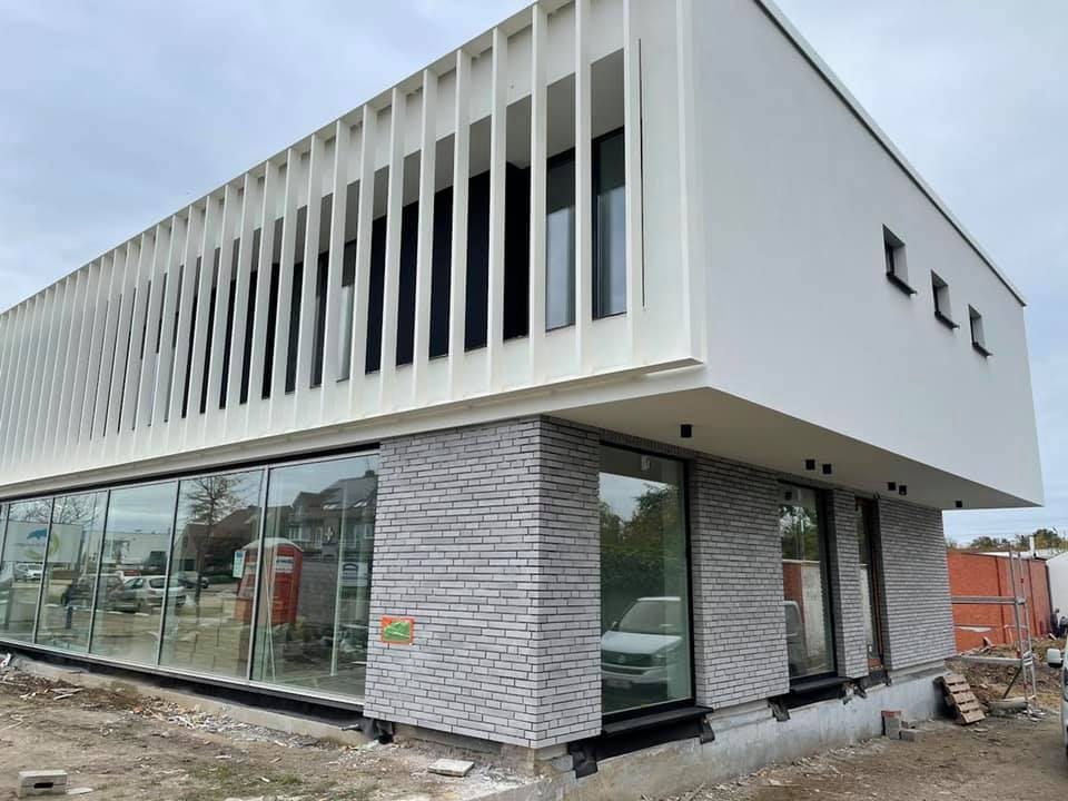 Kantoorgebouw met witte gevelbepleistering en grijze steenstrips als plint