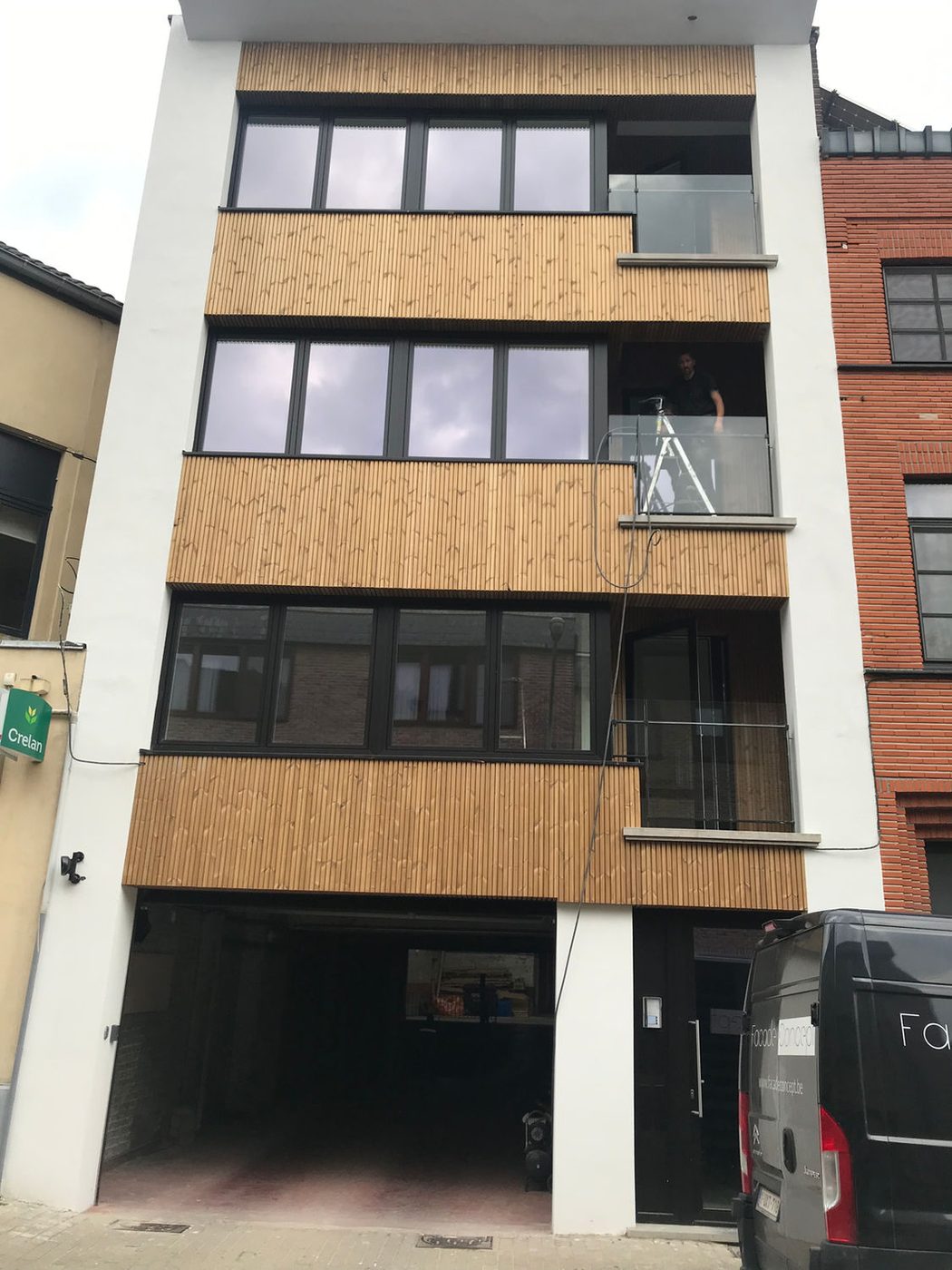 Appartementsgebouw met witte gevelbepleistering en houten gevelbekleding rond de terrassen
