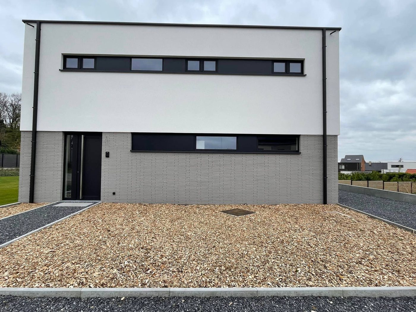 Nieuwbouwwoning met witte crepi en donkergrijze geveldelen