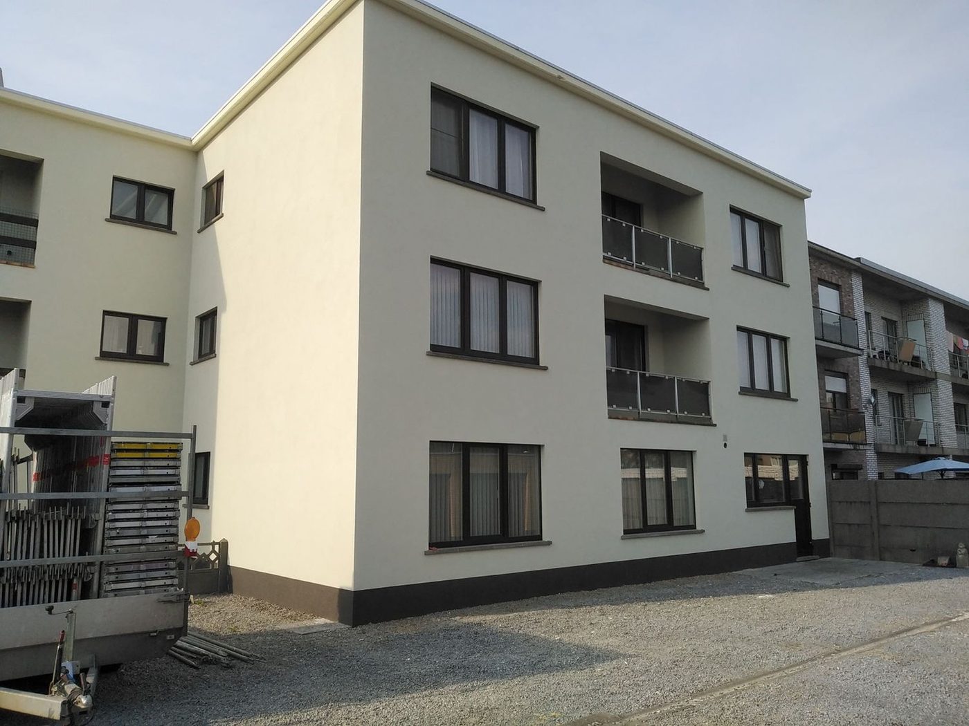 Appartementsgebouw met crèmekleurige gevelbepleistering en donkere plint