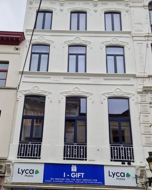 Gerenoveerde herenwoning met witte gevelbepleistering en bewaarde ornamenten