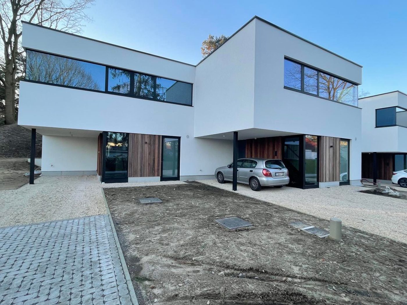 Moderne villa met witte crepi en houten accenten aan de inkom